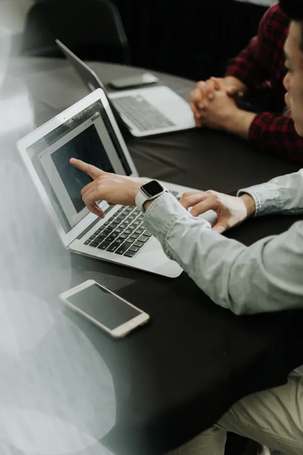 Twee mensen bekijken samen een laptop aan een werktafel.
